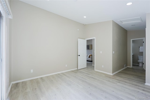 spare room with attic access, light wood-style flooring, recessed lighting, and baseboards