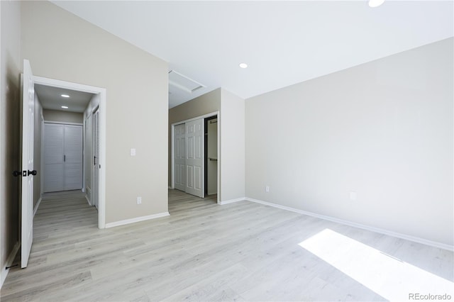 unfurnished bedroom featuring a closet, baseboards, attic access, and light wood-style flooring