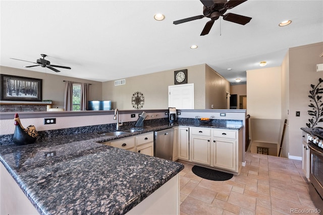 kitchen with appliances with stainless steel finishes, sink, dark stone countertops, and kitchen peninsula