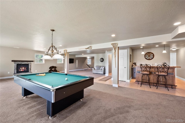 rec room featuring bar, pool table, a textured ceiling, light colored carpet, and a fireplace