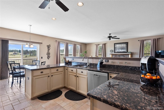 kitchen with pendant lighting, dishwasher, sink, and dark stone countertops