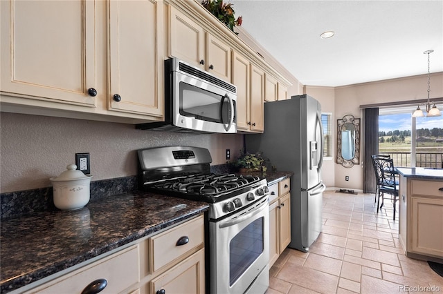 kitchen featuring pendant lighting, cream cabinets, dark stone counters, and appliances with stainless steel finishes