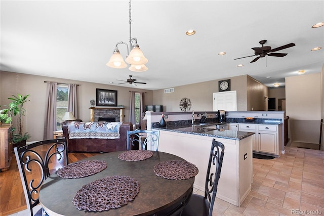 dining area with ceiling fan, sink, and a fireplace