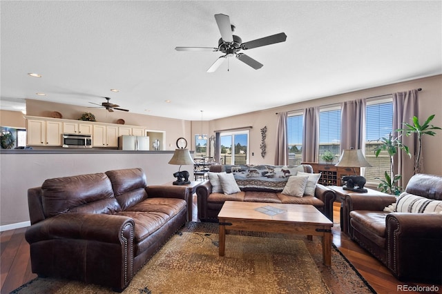 living room featuring dark wood-type flooring, a textured ceiling, and ceiling fan