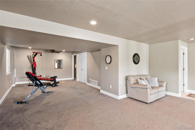 exercise area featuring ceiling fan, a textured ceiling, and carpet