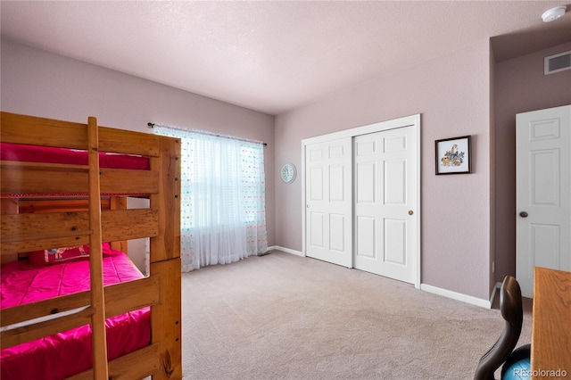 bedroom with light carpet, a textured ceiling, and a closet