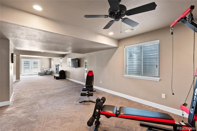 exercise area with french doors, ceiling fan, carpet floors, and a textured ceiling