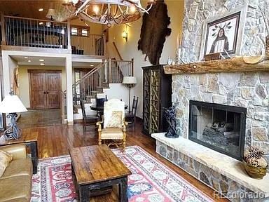 59 Club House Road 1/2Quarter Share D, Breckenridge, CO 80424 - living room featuring stairway, wood finished floors, a towering ceiling, a chandelier, and a stone fireplace
