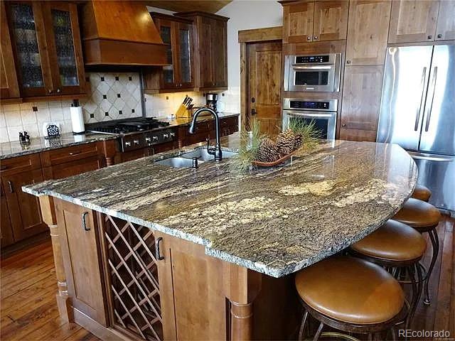 59 Club House Road 1/2Quarter Share D, Breckenridge, CO 80424 - kitchen with stainless steel fridge, premium range hood, gas stovetop, dark wood-type flooring, and dark stone counters