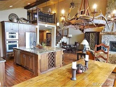 59 Club House Road 1/2Quarter Share D, Breckenridge, CO 80424 - kitchen with dark wood-type flooring, stainless steel appliances, a center island with sink, light stone countertops, and a stone fireplace