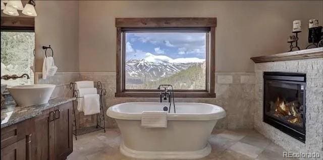 59 Club House Road 1/2Quarter Share D, Breckenridge, CO 80424 - bathroom featuring vanity, a freestanding bath, tile walls, healthy amount of natural light, and a glass covered fireplace