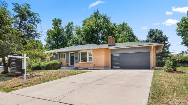 2963 S Vrain St, Denver, CO 80236 - ranch-style home featuring an attached garage, driveway, a chimney, brick siding, and a front lawn