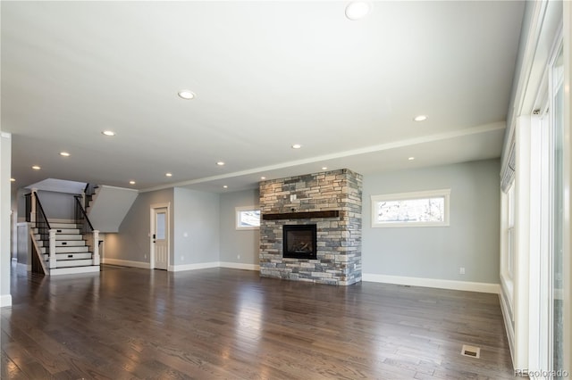 unfurnished living room featuring dark hardwood / wood-style flooring, a wealth of natural light, and a stone fireplace