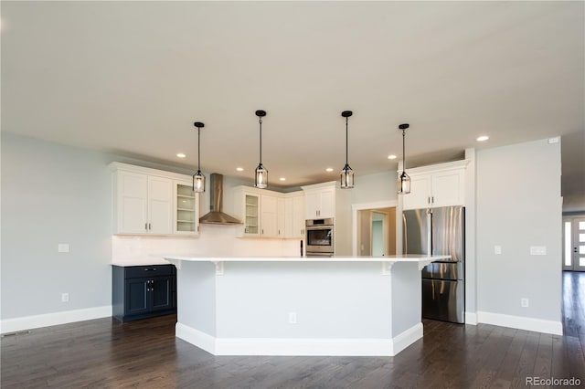 kitchen featuring decorative light fixtures, a kitchen bar, stainless steel appliances, and wall chimney exhaust hood