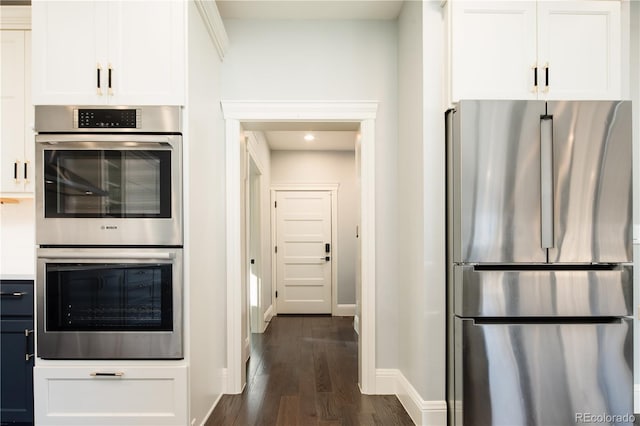 kitchen with stainless steel appliances, dark hardwood / wood-style flooring, and white cabinetry