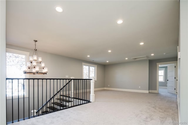 hall with light carpet and a notable chandelier