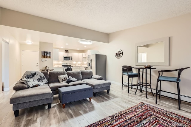 3144 S Wheeling Way Unit 401, Aurora, CO 80014 - living area featuring light wood-type flooring, baseboards, and a textured ceiling