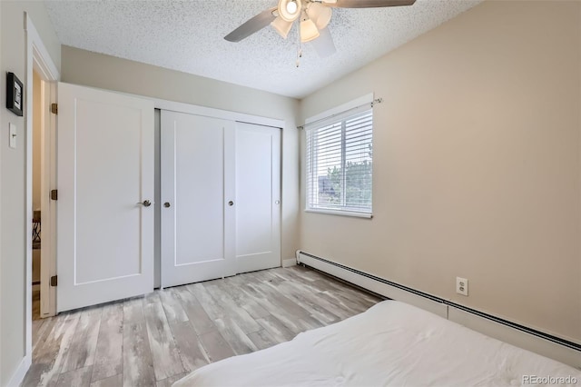 3144 S Wheeling Way Unit 401, Aurora, CO 80014 - bedroom with a baseboard radiator, light wood finished floors, a closet, a textured ceiling, and baseboards