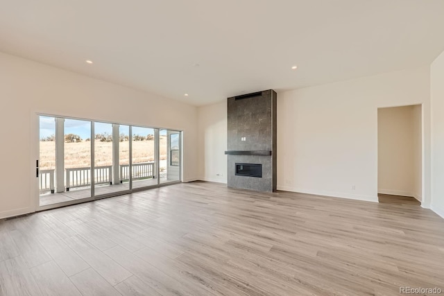 unfurnished living room with a large fireplace, baseboards, light wood-style floors, and recessed lighting