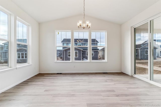 unfurnished dining area featuring a notable chandelier, a healthy amount of sunlight, vaulted ceiling, and light hardwood / wood-style floors