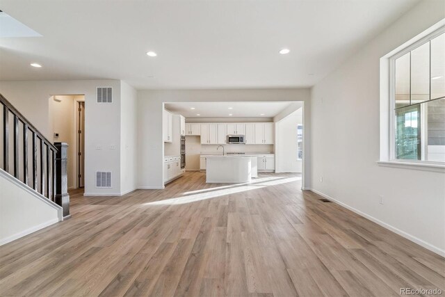 unfurnished living room with light wood-type flooring and sink