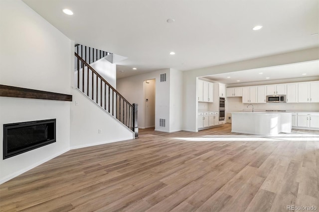 unfurnished living room featuring light wood-type flooring and sink