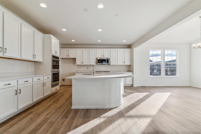 kitchen with light hardwood / wood-style floors, white cabinetry, and appliances with stainless steel finishes