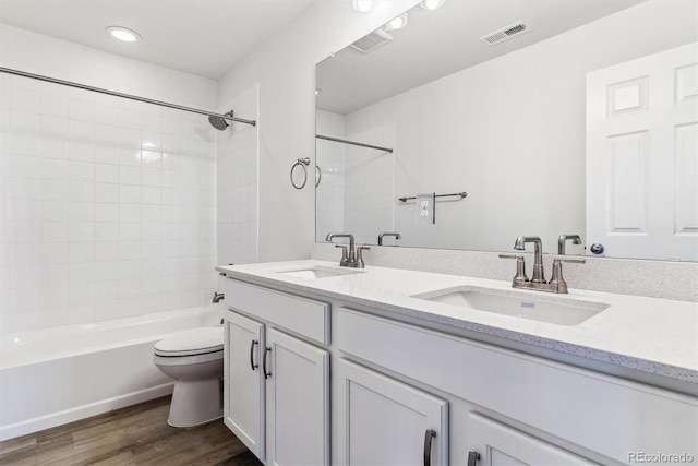 full bathroom featuring vanity, hardwood / wood-style flooring, toilet, and tiled shower / bath