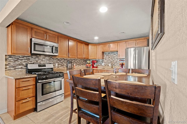 kitchen with appliances with stainless steel finishes, light tile patterned flooring, recessed lighting, and decorative backsplash