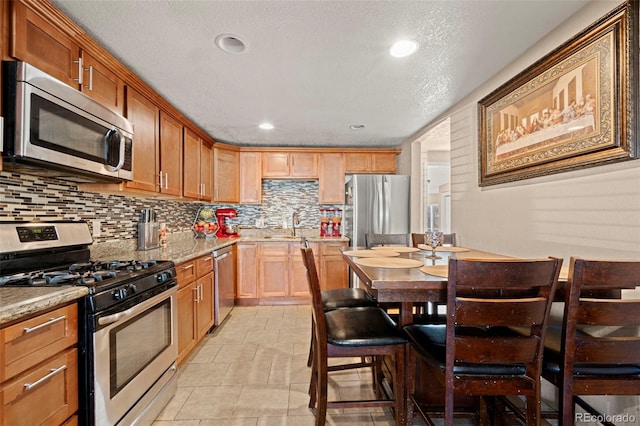 kitchen featuring light stone counters, stainless steel appliances, backsplash, and recessed lighting