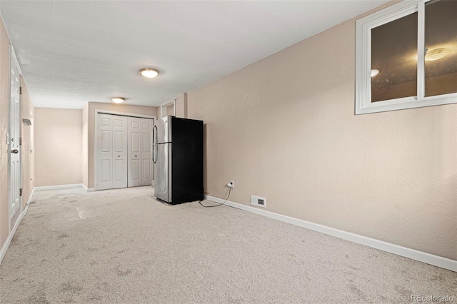 empty room with baseboards, visible vents, and light colored carpet