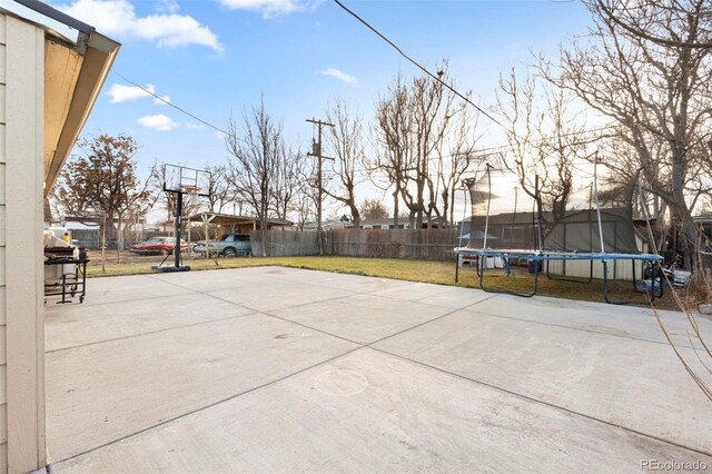 view of sport court with a fenced backyard, a trampoline, and a lawn