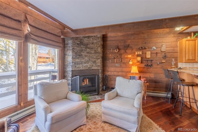 living area featuring hardwood / wood-style flooring, a stone fireplace, and baseboard heating