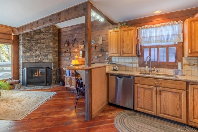 kitchen with dishwasher, a stone fireplace, sink, and dark wood-type flooring