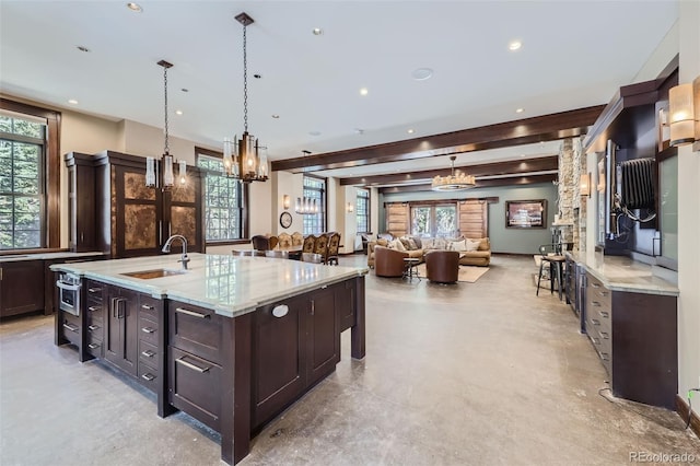 kitchen with a sink, dark brown cabinetry, plenty of natural light, light stone counters, and recessed lighting