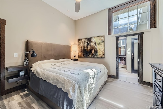 bedroom featuring light wood finished floors, a high ceiling, and ceiling fan