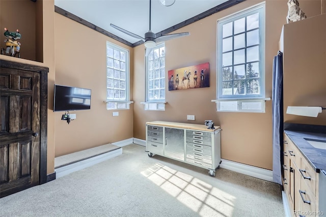 interior space featuring light carpet, baseboards, and a ceiling fan
