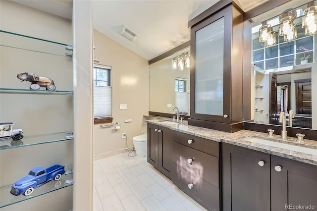 bathroom with vaulted ceiling, toilet, double vanity, baseboards, and tile patterned flooring