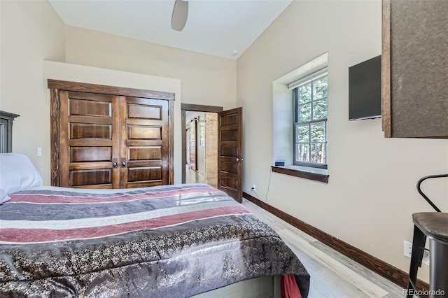 bedroom with wood finished floors, baseboards, vaulted ceiling, and ceiling fan