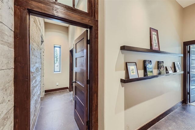 hallway featuring finished concrete flooring and baseboards