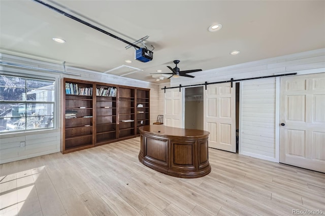 unfurnished office featuring a barn door, light wood-style flooring, and recessed lighting