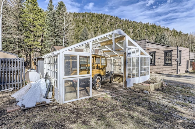 view of greenhouse featuring a forest view