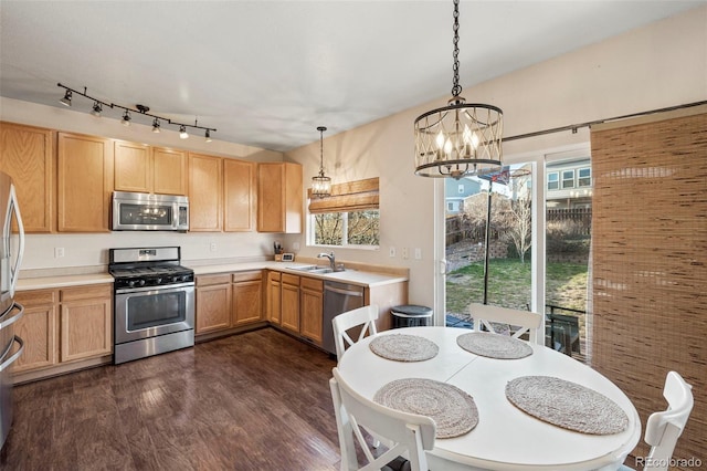 kitchen featuring dark wood-style flooring, a sink, light countertops, appliances with stainless steel finishes, and decorative light fixtures