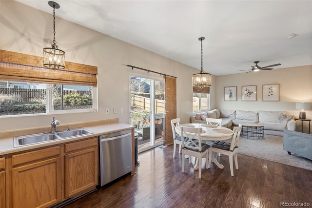 kitchen featuring pendant lighting, light countertops, open floor plan, a sink, and dishwasher