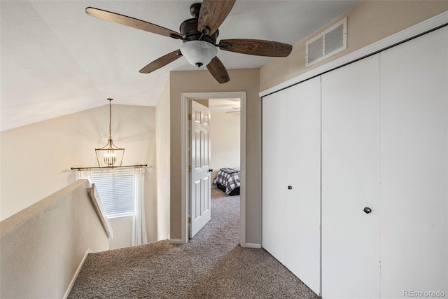 corridor with carpet, lofted ceiling, visible vents, an upstairs landing, and a chandelier