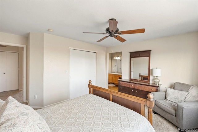 bedroom featuring a closet, a ceiling fan, light carpet, a sink, and ensuite bath