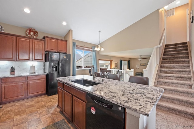 kitchen featuring an island with sink, lofted ceiling, sink, decorative backsplash, and black appliances