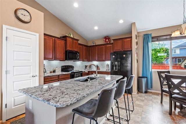 kitchen featuring sink, tasteful backsplash, light stone counters, a kitchen island with sink, and black appliances