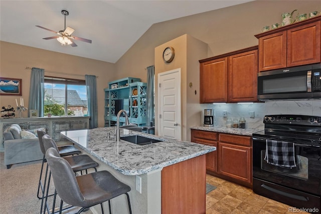 kitchen featuring sink, black range with electric stovetop, tasteful backsplash, a center island with sink, and vaulted ceiling