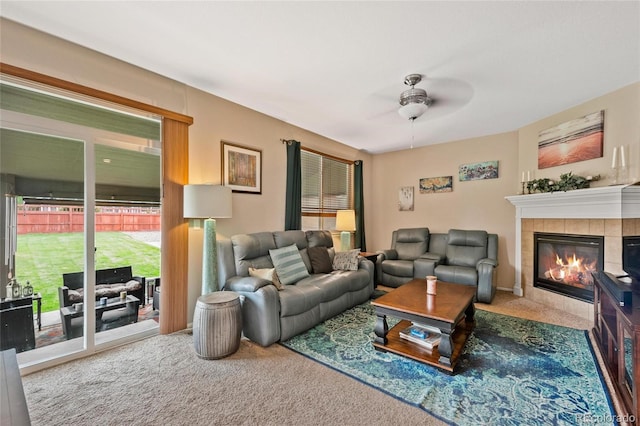 carpeted living room with a tile fireplace and ceiling fan